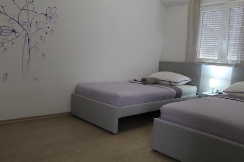 a bedroom with two beds and a window at Holiday home Villa Anny in Brodarica