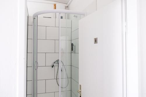 um chuveiro na casa de banho com azulejos brancos em Hammerbrook Hostel em Hamburgo