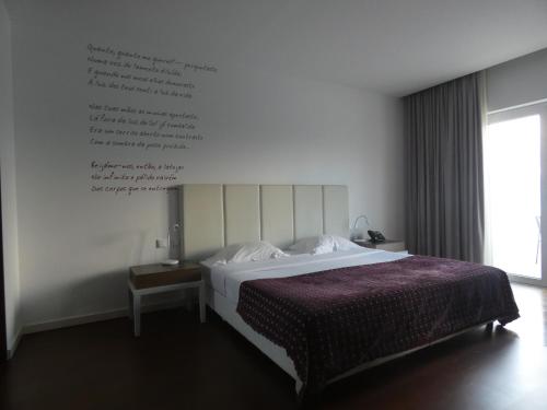a bedroom with a bed and a writing on the wall at Hotel Vila D'Óbidos in Óbidos