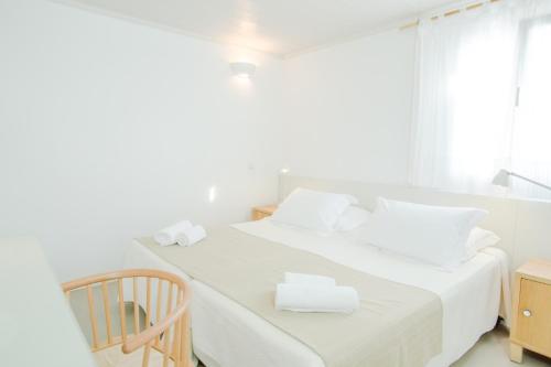 a white bedroom with a bed with white sheets and white pillows at Agnandi Cielo in Tourlos