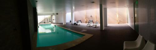 a swimming pool in a building with chairs around it at Hotel Vila D'Óbidos in Óbidos