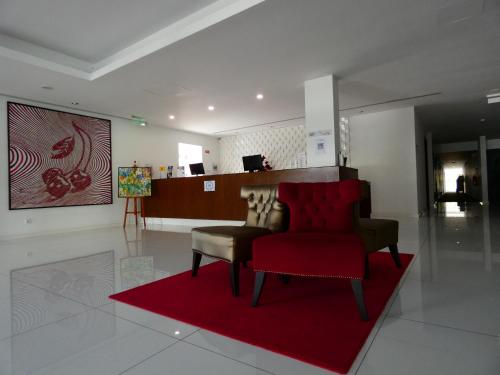 a living room with a red chair and a red rug at Hotel Vila D'Óbidos in Óbidos