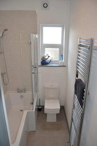 a bathroom with a toilet and a shower and a window at The Moo House 2 bed Property - STAYSEEKERS in Salisbury