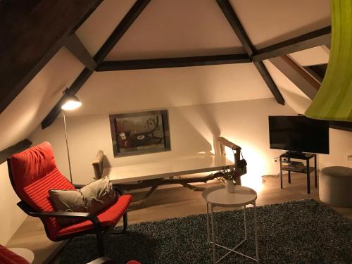 a living room with a red chair and a television at B&B Logeren bij de burgemeester in Stad aan ʼt Haringvliet