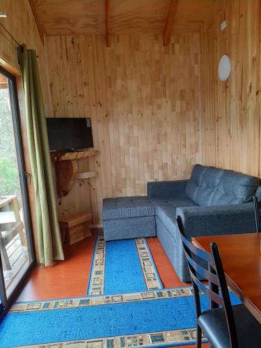 Una sala de estar con un sofá azul y un televisor en Cabañas Genesis, en Choshuenco