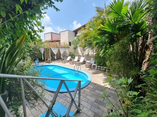 a pool with a table and chairs in a yard at Pousada Beijos y Abraços in Natal