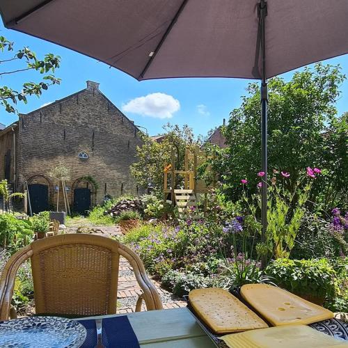 an umbrella sitting on a table in a garden at B&B Logeren bij de burgemeester in Stad aan ʼt Haringvliet