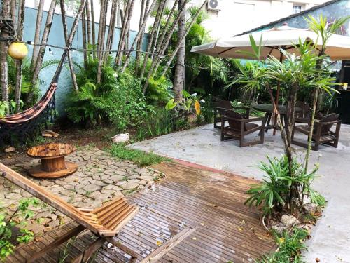 eine Terrasse mit einer Hängematte sowie einem Tisch und Stühlen in der Unterkunft Tombo Beach Hostel & Pousada in Guarujá