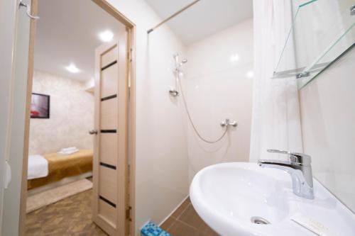 a white bathroom with a sink and a shower at Hotel Moonlight in Tula