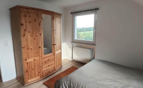 a bedroom with a wooden cabinet and a bed at Ferienwohnung Sonne in Beltheim