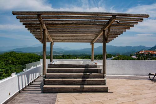 a wooden pergola with a hot tub on a patio at LA LOMA SUITES in Ixtapa