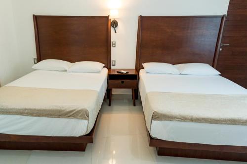 a bedroom with two beds and a night stand at LA LOMA SUITES in Ixtapa