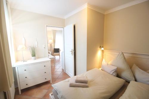 een slaapkamer met een bed en een dressoir met een spiegel bij Haus am Park Wohnung Nr1 in Spiekeroog