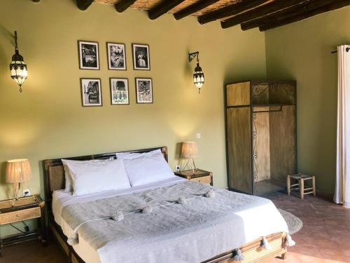 a bedroom with a large bed with two lamps and pictures on the wall at Upupa de l’Atlas in Marrakech