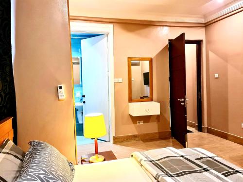 ein Schlafzimmer mit einem Bett und einer gelben Lampe in der Unterkunft Adepa Court Luxury Apartment Services in Kumasi