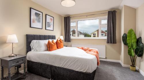 Un dormitorio con una cama con almohadas naranjas y una ventana. en Leeward House - Donnini Apartments, en Ayr