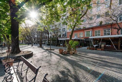 a cobblestone street in a city with trees and benches at Petra Inn Apartments in historical palace Bratislava in Bratislava