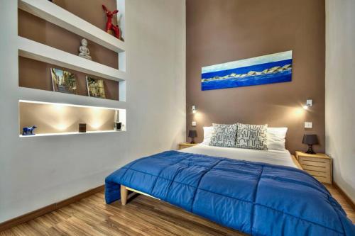 een slaapkamer met een bed met een blauwe deken bij Valletta Timeless Elegance : City Centre Apartment in Valletta