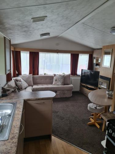 a kitchen and a living room with a couch at Carmels Caravan Borwick Lakes in Carnforth