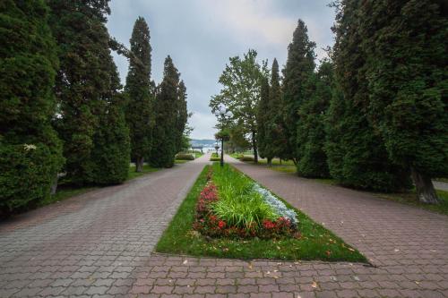a brick road with a garden of flowers and trees at Mrągowo dwupoziomowy Apartament Indygo 85m2 z widokiem na jezioro in Mrągowo