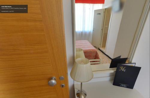 Habitación con puerta, espejo y lámpara. en Hotel Villa Ginevra, en Cavallino-Treporti