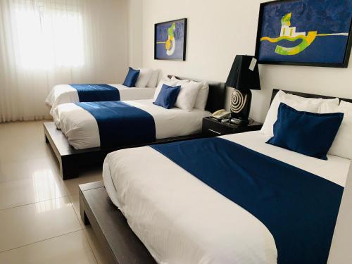 a hotel room with three beds with blue and white sheets at Hotel Galerias HN in San Pedro Sula