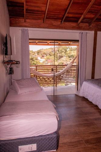 a bedroom with two beds and a view of a balcony at Pousada Makani, no centrinho do Rosa in Praia do Rosa