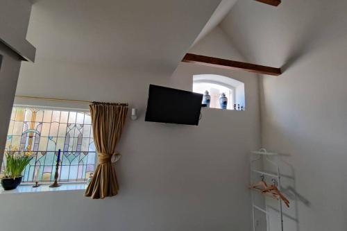 a flat screen tv on a wall next to a window at Oranjerie, 7 km onder Groningen in Paterswolde