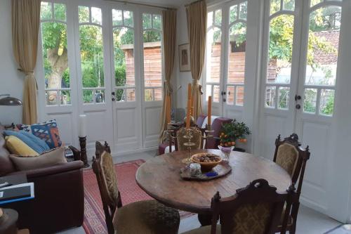 a living room with a table and chairs and windows at Oranjerie, 7 km onder Groningen in Paterswolde