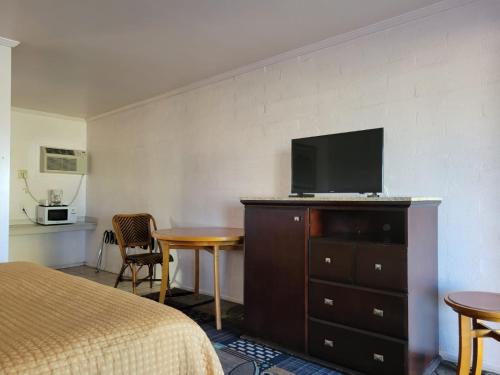 a hotel room with a bed and a television on a dresser at Emerald Inn & Lounge in Blythe