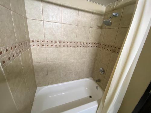 y baño con bañera blanca y ducha. en Super 8 by Wyndham Rocky Mount I-95 EXIT 145 en Battleboro