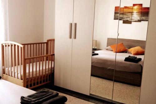 ein Schlafzimmer mit einem Kinderbett, einem Bett und einem Glasschrank in der Unterkunft Casa Leyva in Chiavari
