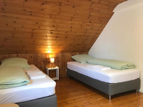 two beds in a room with a wooden ceiling at Townus Apartments Heidenrod in Zorn