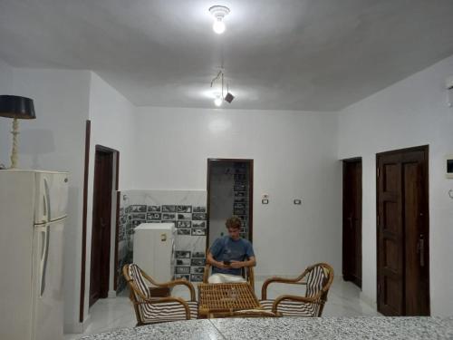 a person sitting at a table in a kitchen with chairs at Jamaica Guest House in Aswan
