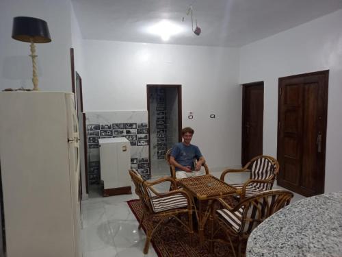 a man sitting at a table in a room with chairs at Jamaica Guest House in Aswan