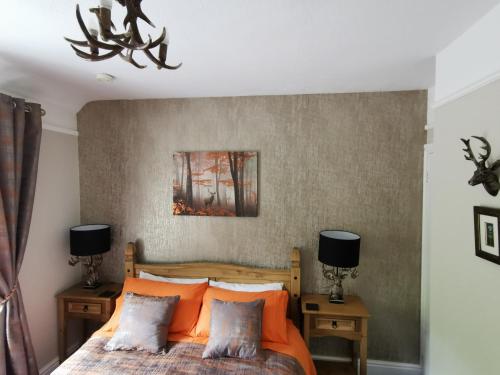 a bedroom with a bed with orange pillows at Dolweunydd Bed and Breakfast in Betws-y-coed