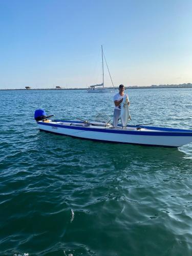 a man sitting on a blue boat with a fish at Karpa House in Sottomarina