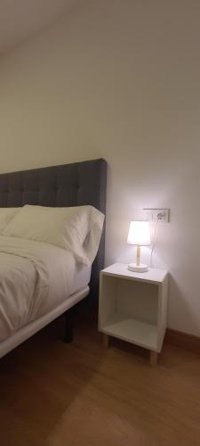a bed with a nightstand with a lamp on it at APARTAMENTO FRANJA 50 Gastromaar in A Coruña