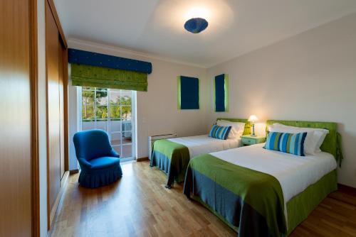 1 dormitorio con 2 camas y silla azul en Villa Wilker, en Vilamoura