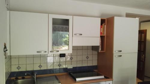 una cucina con armadi bianchi, lavandino e finestra di Appartamento Modena Park a Modena