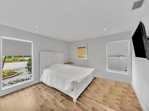 SuperVilla - 3BR/2BA - Pool - Walk to beach في هوليوود: غرفة نوم بيضاء مع سرير وتلفزيون بشاشة مسطحة