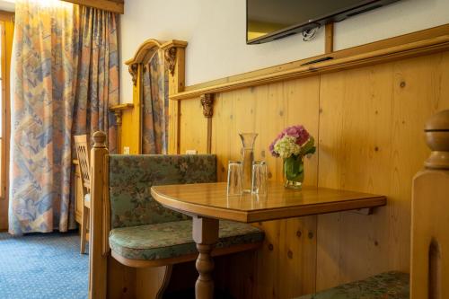 a table and a chair with a vase of flowers on it at Posthotel Erlerwirt in Erl