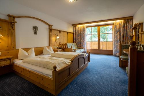 a bedroom with a large bed and a large window at Posthotel Erlerwirt in Erl