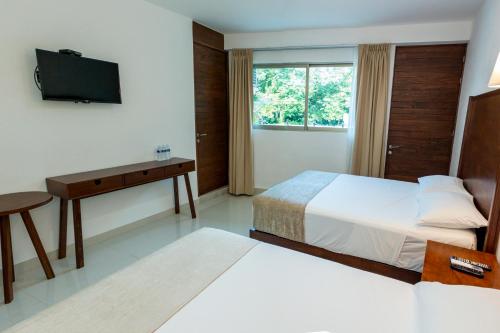 a hotel room with a bed and a desk and a television at LA LOMA SUITES in Ixtapa