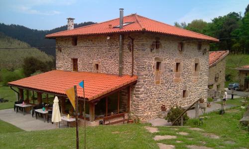 a large stone building with a red roof at Casa Rural Pikatzaenea in Sopuerta