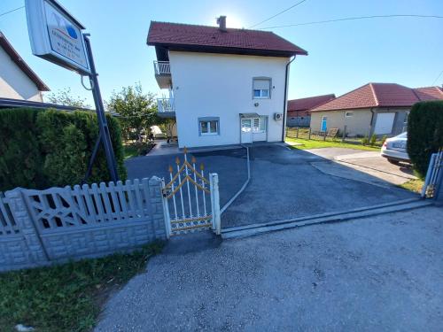 un edificio bianco con una recinzione di fronte di Apartmani Denis a Dubrave Gornje