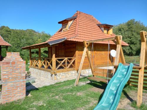 a playground with a house and a slide at Apartment Mateja in Mokra Gora