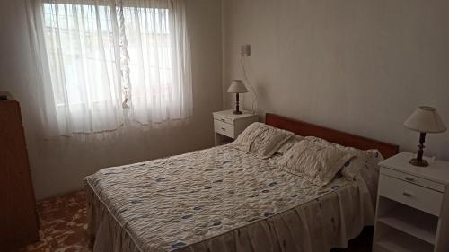 ein Schlafzimmer mit einem Bett, zwei Nachttischen und einem Fenster in der Unterkunft Departamento 2 ambientes 1er piso in Gualeguay