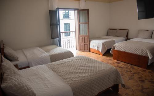 a room with three beds and a door with a window at Hotel Lili - Popayán in Popayan