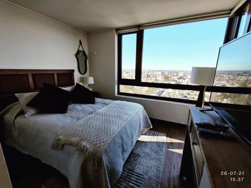 a bedroom with a large bed and large windows at Departamento de primer Nivel in Chillán